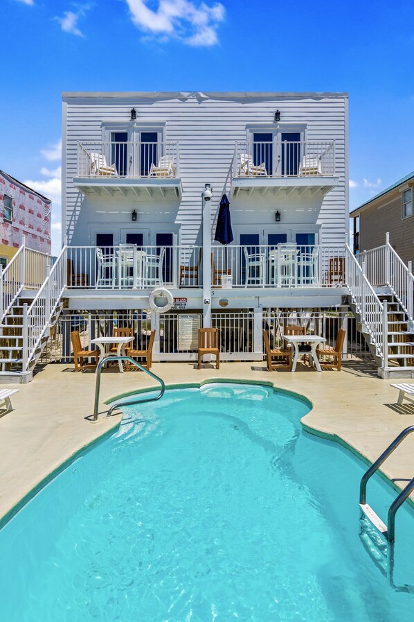 Un bâtiment à deux étages doté d’une piscine, d’un espace extérieur aménagé et d’un escalier menant à l’étage supérieur.