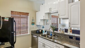 A kitchen with white cabinets, a granite countertop, a refrigerator, a dishwasher, and a stove. - Gulf Shores Duplex Beachfront Pool -4bd  (Gulf Shores)