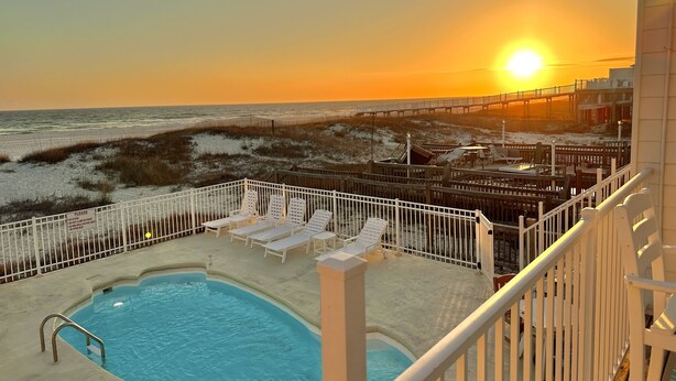 A pool area with lounge chairs and a view of the beach at sunset. - Gulf Shores Duplex Beachfront Pool -4bd  (Gulf Shores)
