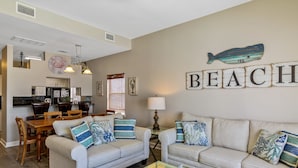 A living room with two sofas, a coffee table, and a dining area with a table and chairs. - Gulf Shores Duplex Beachfront Pool -4bd  (Gulf Shores)