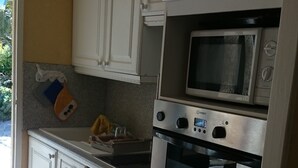 Een compacte keuken met witte kastjes, een magnetron en een oven.