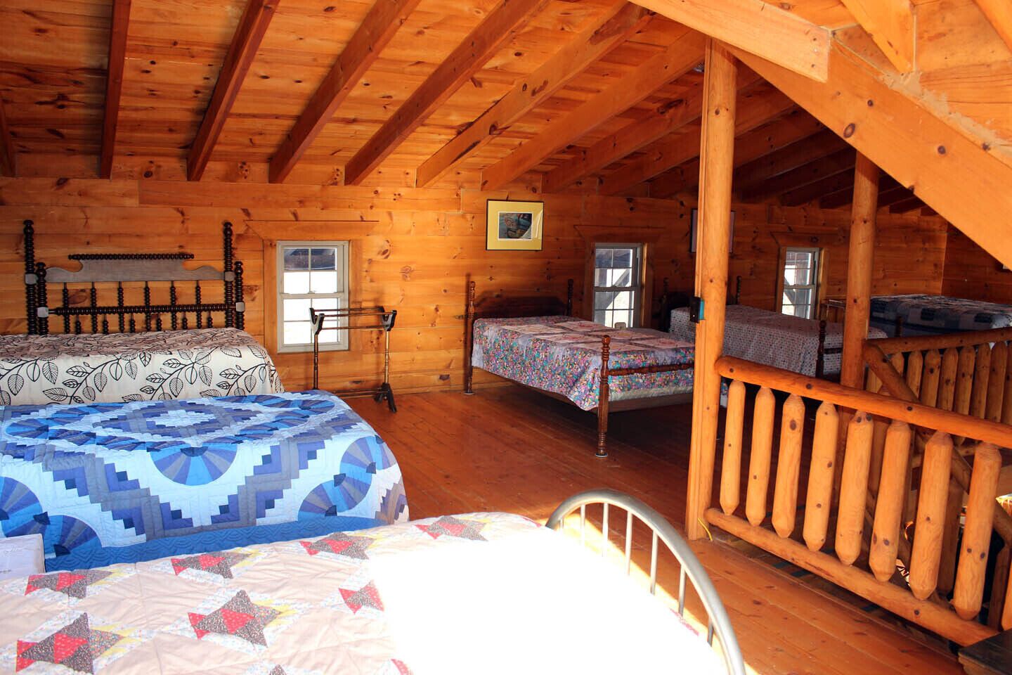 Eine Hütte mit zwei Schlafzimmern, jeweils mit einem Holzbett und einem Fenster.