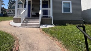 A two-story residential building with a front porch, a visible address sign, and a pathway leading to the entrance. - Cozy Condo in Downtown Roanoke VA 
 (Roanoke)