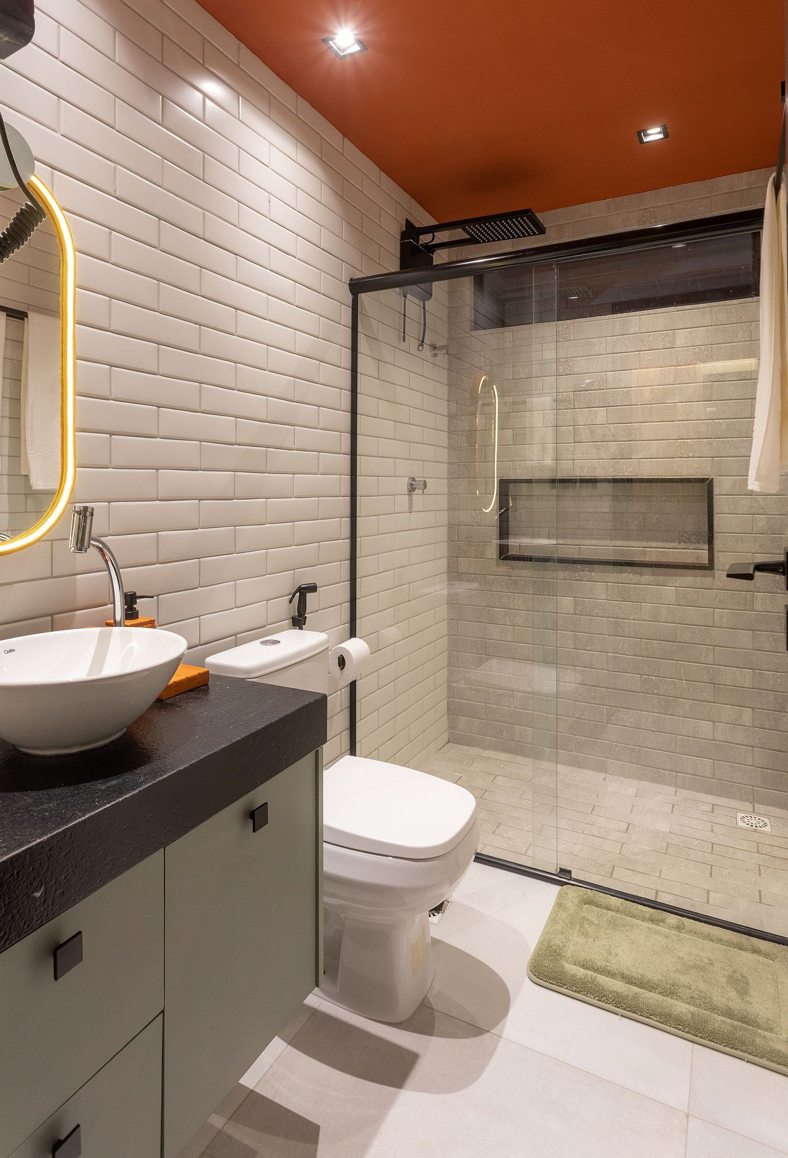 Un baño moderno con lavamanos blanco, inodoro y cabina de ducha con mampara de vidrio.