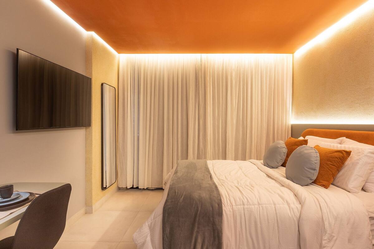 A modern hotel room with a bed, a flat-screen TV, and a desk with a chair.