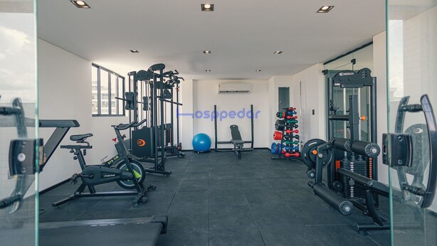 Un gimnasio con equipamiento de ejercicio, una pelota de pilates azul y un soporte para pesas.