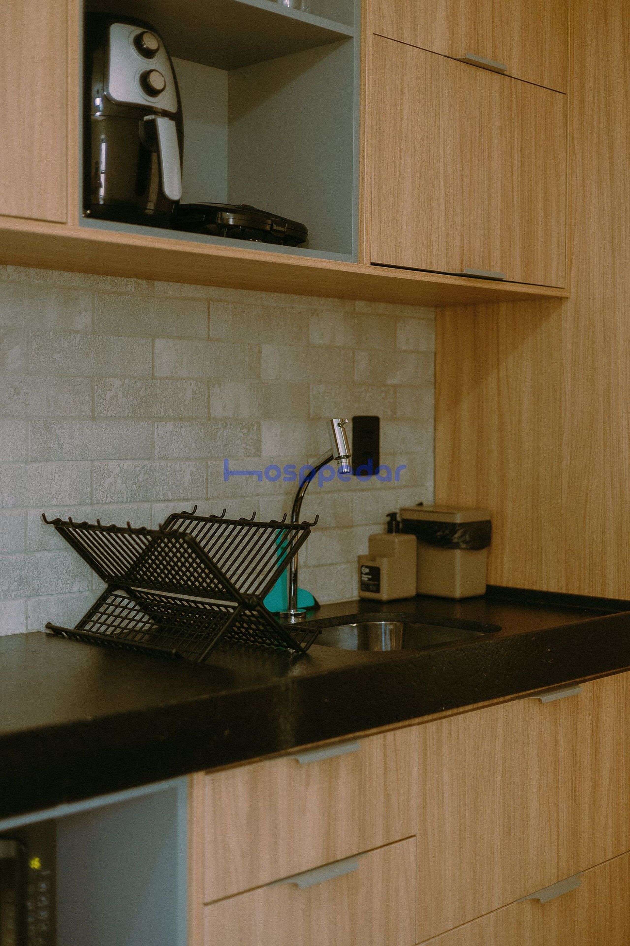 Una cocina con cafetera, un lavabo y una estantería metálica sobre la encimera.
