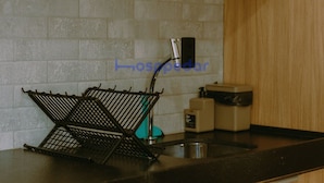 Una cocina con cafetera, un lavabo y una estantería metálica sobre la encimera.