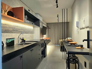 Una cocina moderna con horno empotrado, lavaplatos y comedor con taburetes.