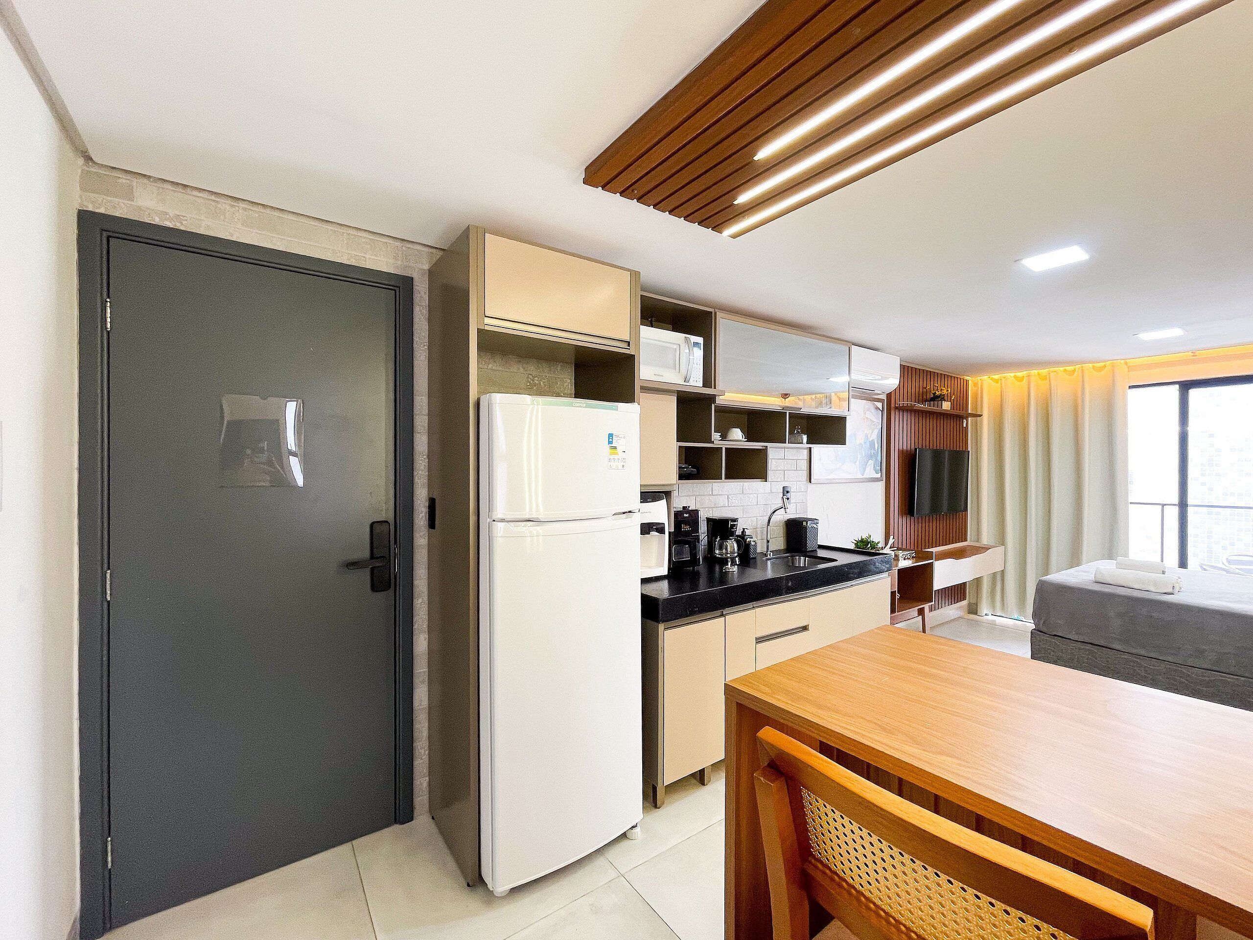 Una cocina compacta equipada con refrigerador, microondas y cafetera.