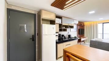 Una cocina compacta equipada con refrigerador, microondas y cafetera.