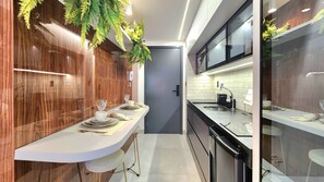 A modern kitchen with a white countertop, wooden wall paneling, and a built-in dishwasher. - Summer Flat by Hosppedar (Cabedelo)