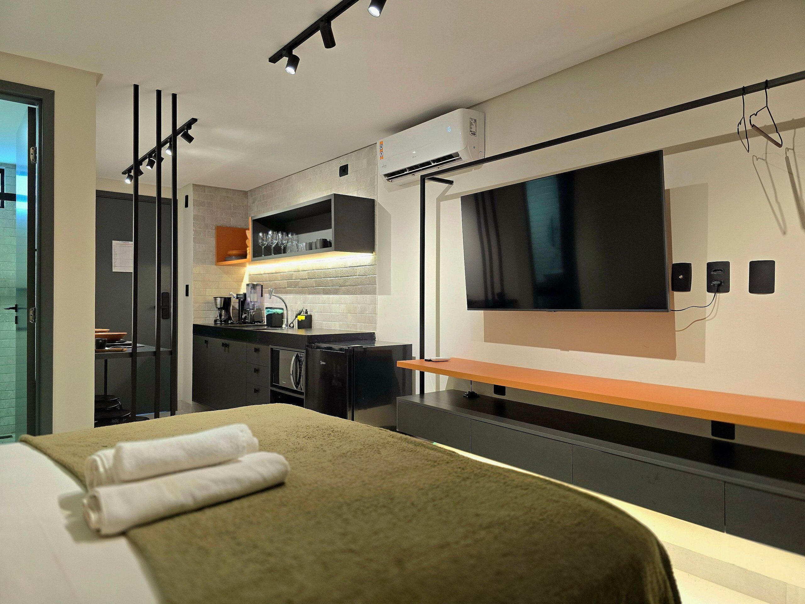 Una habitación de hotel moderna con cama, televisión, kitchenette y baño.