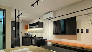 Una habitación de hotel moderna con cama, televisión, kitchenette y baño.