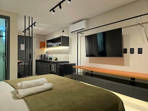 Una habitación de hotel moderna con cama, televisión, kitchenette y baño.