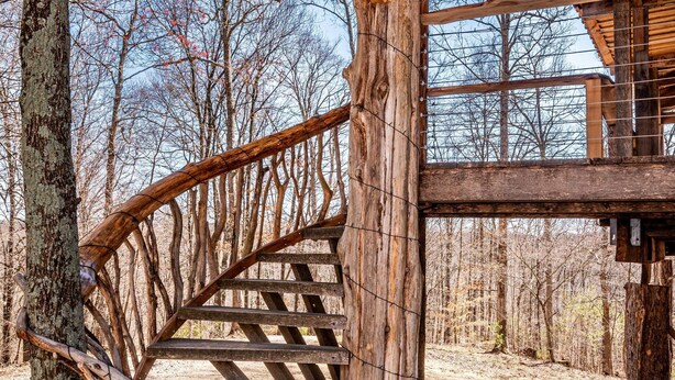 A wooden spiral staircase leading to a covered area with a view of trees and sky. - 2BR, 1BA  HAND BUILT MOUNTAIN TOP TREE HOUSE with Hot tub (Nashville)
