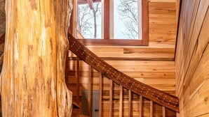 A wooden staircase with a large tree trunk on the left, leading to a room with wooden walls and a window. - 2BR, 1BA  HAND BUILT MOUNTAIN TOP TREE HOUSE with Hot tub (Nashville)