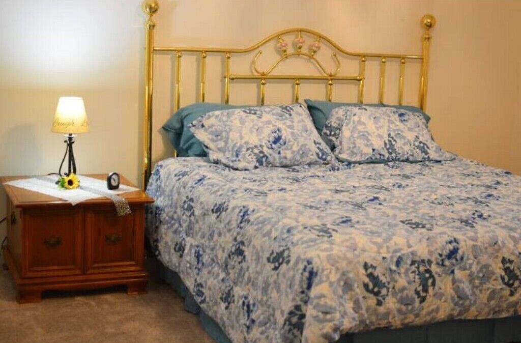 Ein Schlafzimmer mit einem Bett, einem Nachttisch, einer Lampe und einer Uhr.
