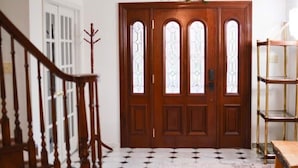 Una puerta doble de madera con paneles de vidrio, una escalera con barandilla de madera y un suelo con diseño.