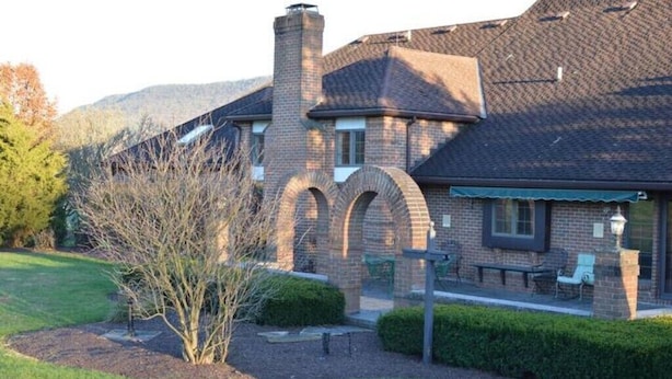 Una casa de ladrillo con chimenea, ventanas arqueadas y un césped bien cuidado.