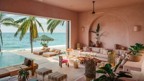 A spacious living area with a large window overlooking the ocean, furnished with a sofa, chairs, and a coffee table.