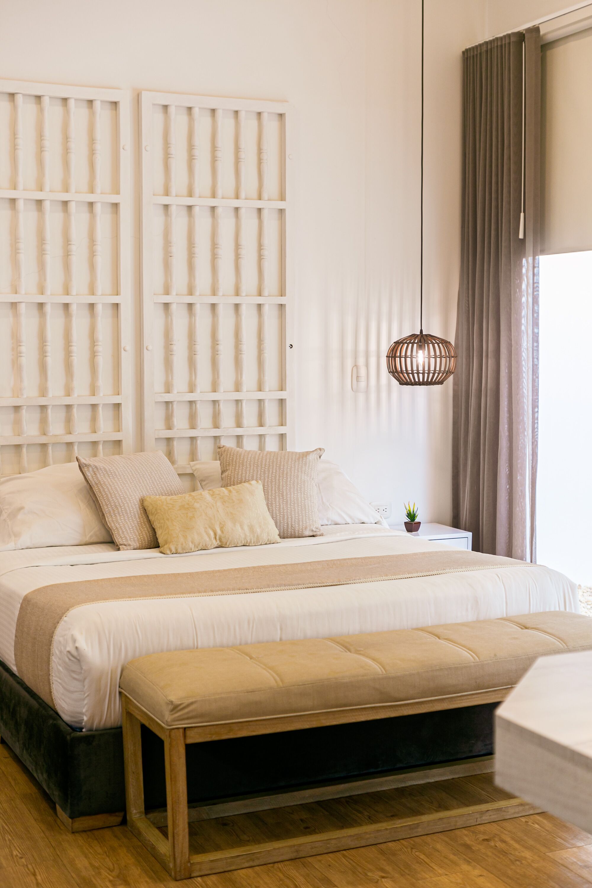 A bedroom with a bed, bedside table, and a hanging light fixture.