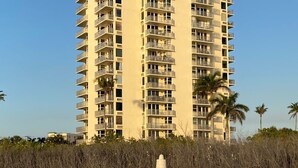 A high-rise hotel with multiple balconies, located near a sandy beach with palm trees. - Fantastic Ft Myers Beachfront Condo! Flexible Check-in Dates and many amenities! (Fort Myers Beach)