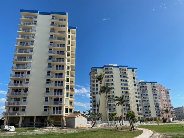 Un edificio residencial alto con varios balcones y un cielo azul despejado.