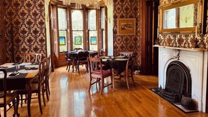 Ein Esszimmer mit einer Chandelüster, Holzmöbeln und einem Kamin.