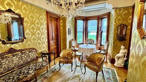 Ein Zimmer mit aufwendigen Möbeln, einer Chandelier und Blick auf Grün.