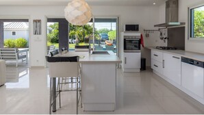 A modern kitchen with a central island, stainless steel appliances, and a view of the outdoors.