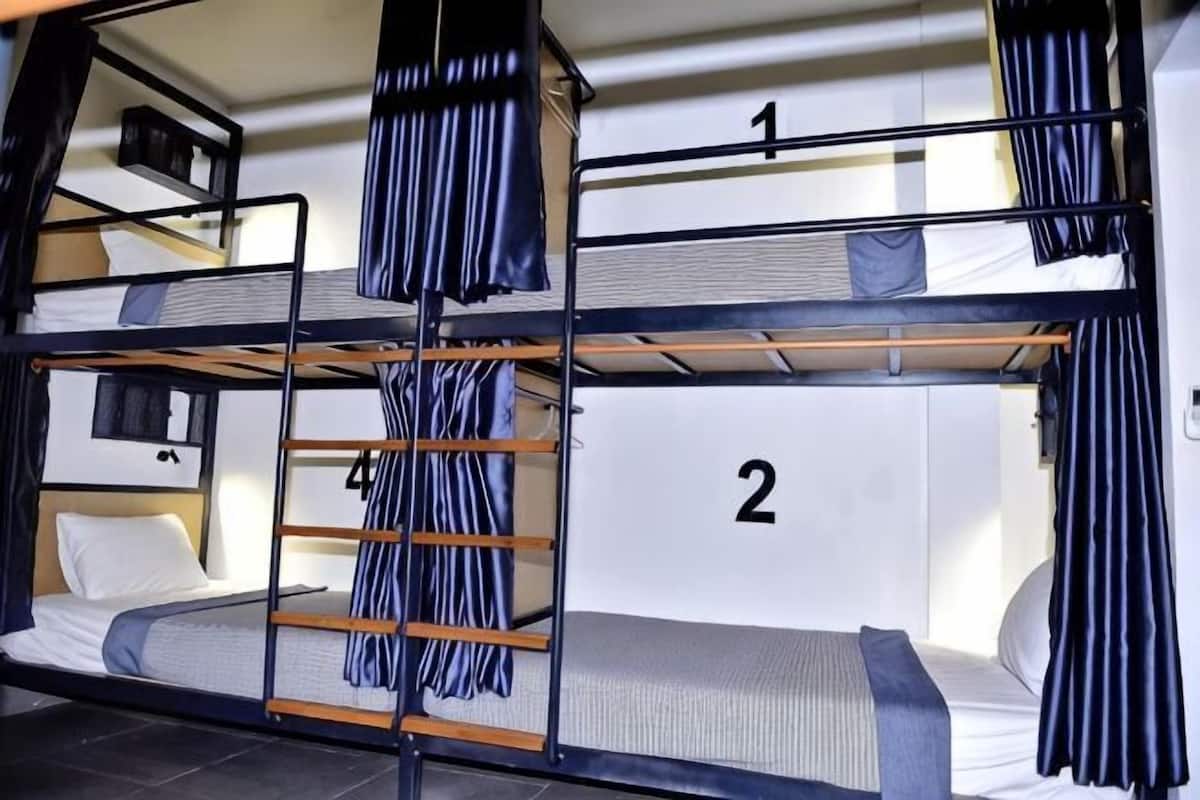 A bunk bed room with a ladder, curtains, and numbered beds.