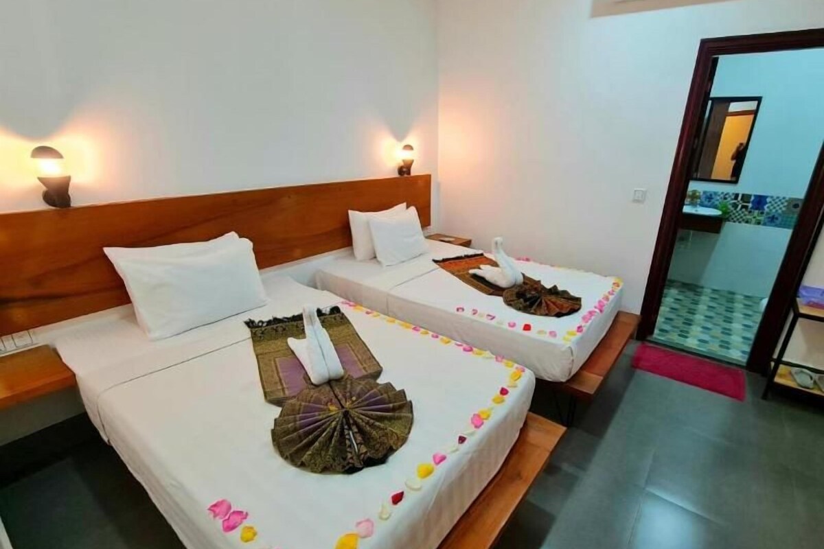 Een hotelkamer met twee bedden, elk met een decoratieve zwaan als middelpunt, wit beddengoed en wandlampen.