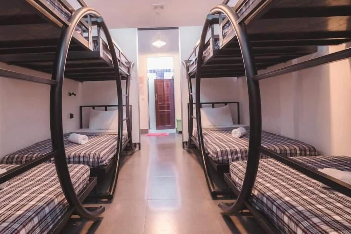 A corridor with bunk beds on either side, leading to a door.