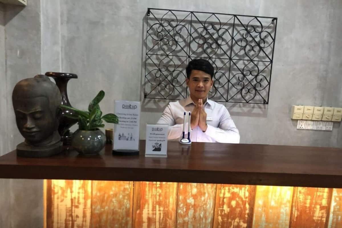 A reception desk with a modern design, a decorative vase, a potted plant, and a sign indicating WiFi availability.