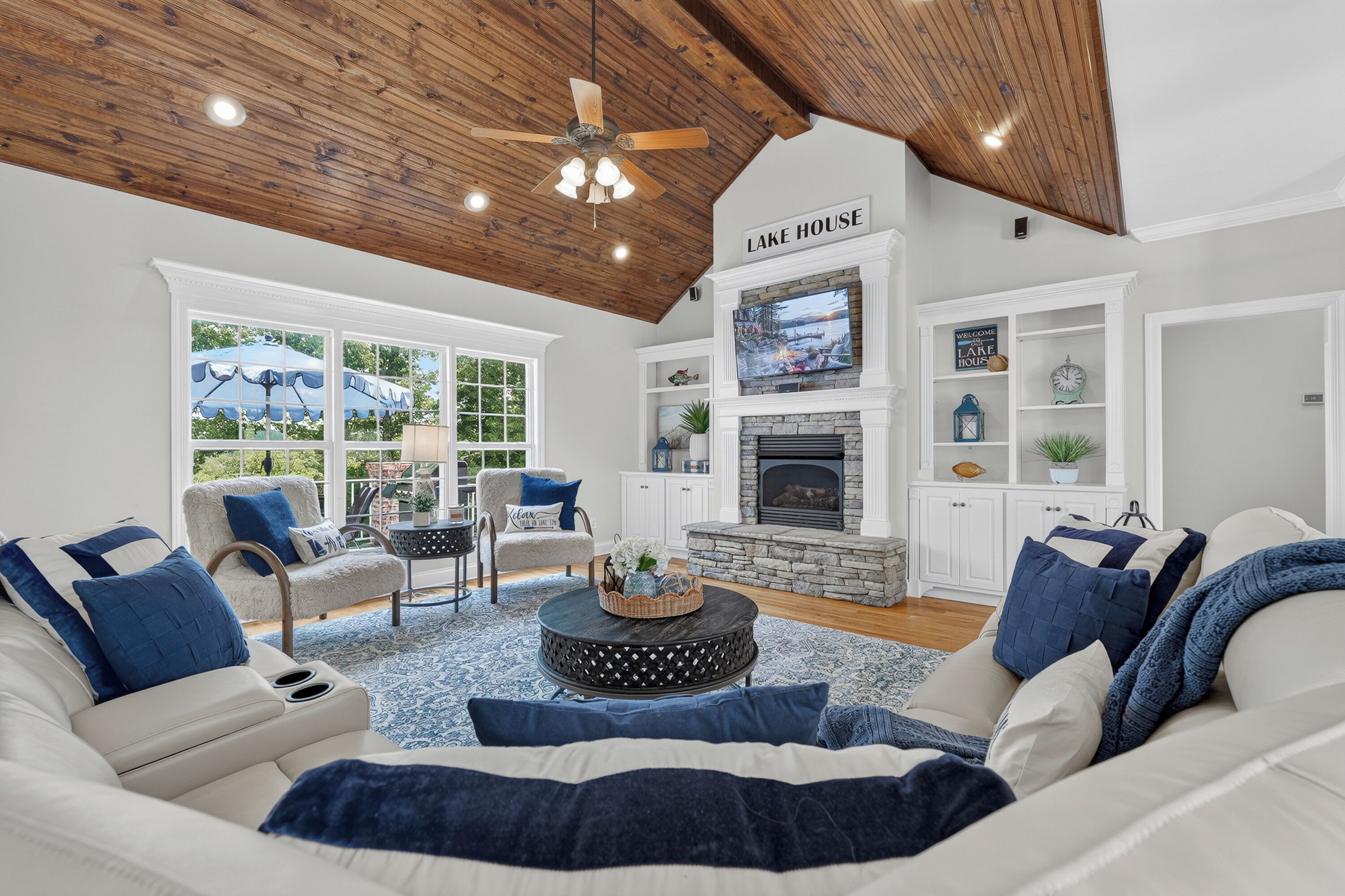 A spacious living room with a high ceiling, a fireplace, and a view of the outdoors.