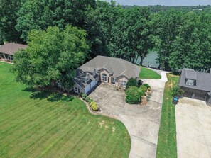 A residential property with a large lawn, a driveway, and a house with a garage.