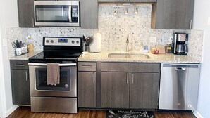 Een moderne keuken met roestvrijstalen apparatuur, een betegelde achterwand en houten kastjes.