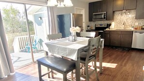 Een moderne keuken met donkere kastjes, een roestvrijstalen koelkast en een magnetron. Er staat een eettafel met stoelen en een bankje.