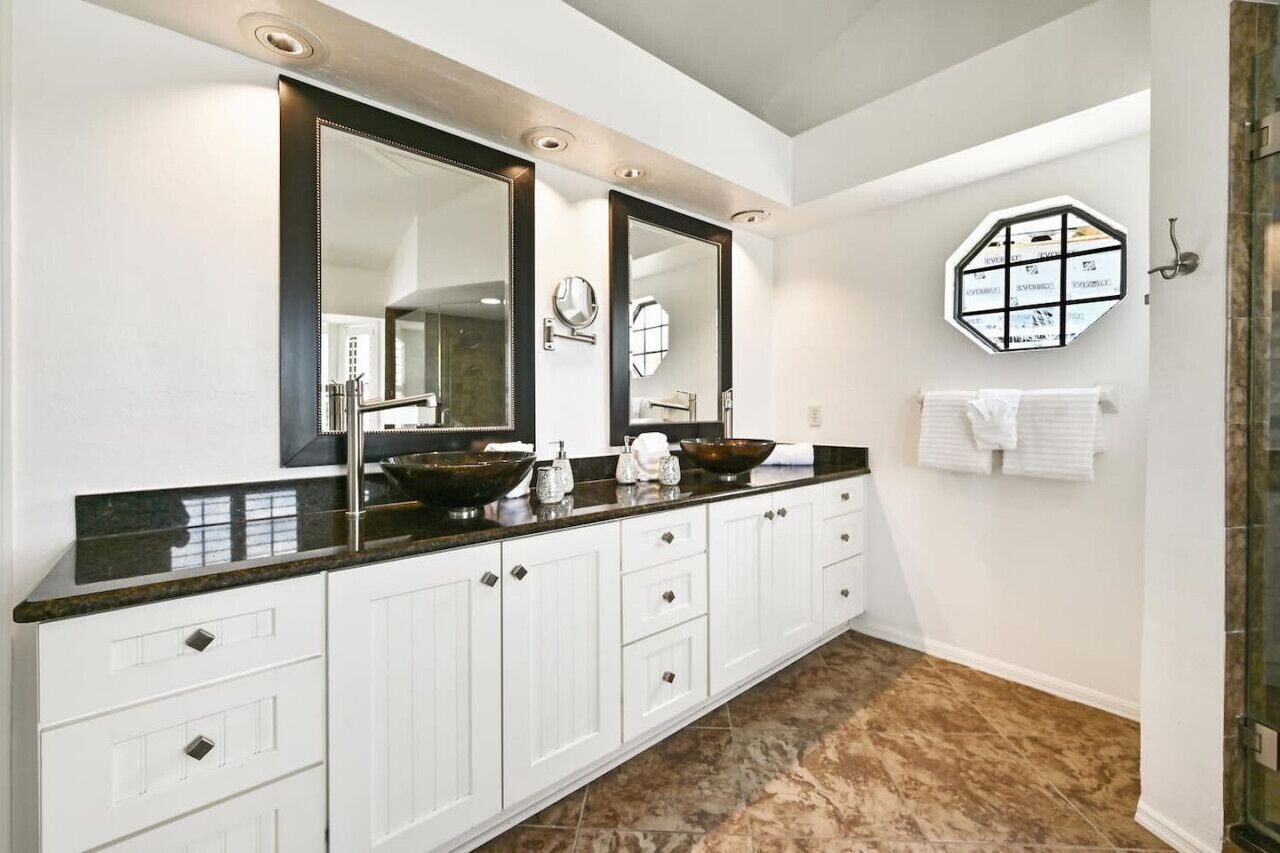 Une salle de bain moderne avec un grand meuble-lavabo, deux miroirs et un élément décoratif hexagonal sur le mur.