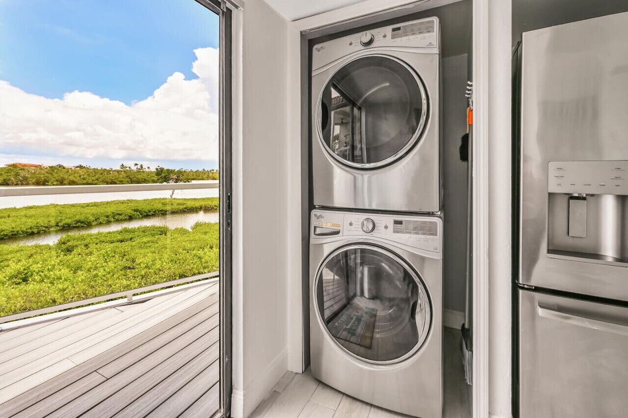 A laundry room with two stainless steel front-loading washers and a refrigerator.
