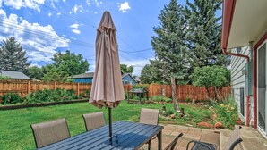 A patio with a table and chairs, surrounded by a wooden fence and a garden. - Sherwood (Colorado Springs)