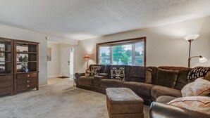 A living room with a sectional sofa, ottoman, and a wooden cabinet. - Sherwood (Colorado Springs)