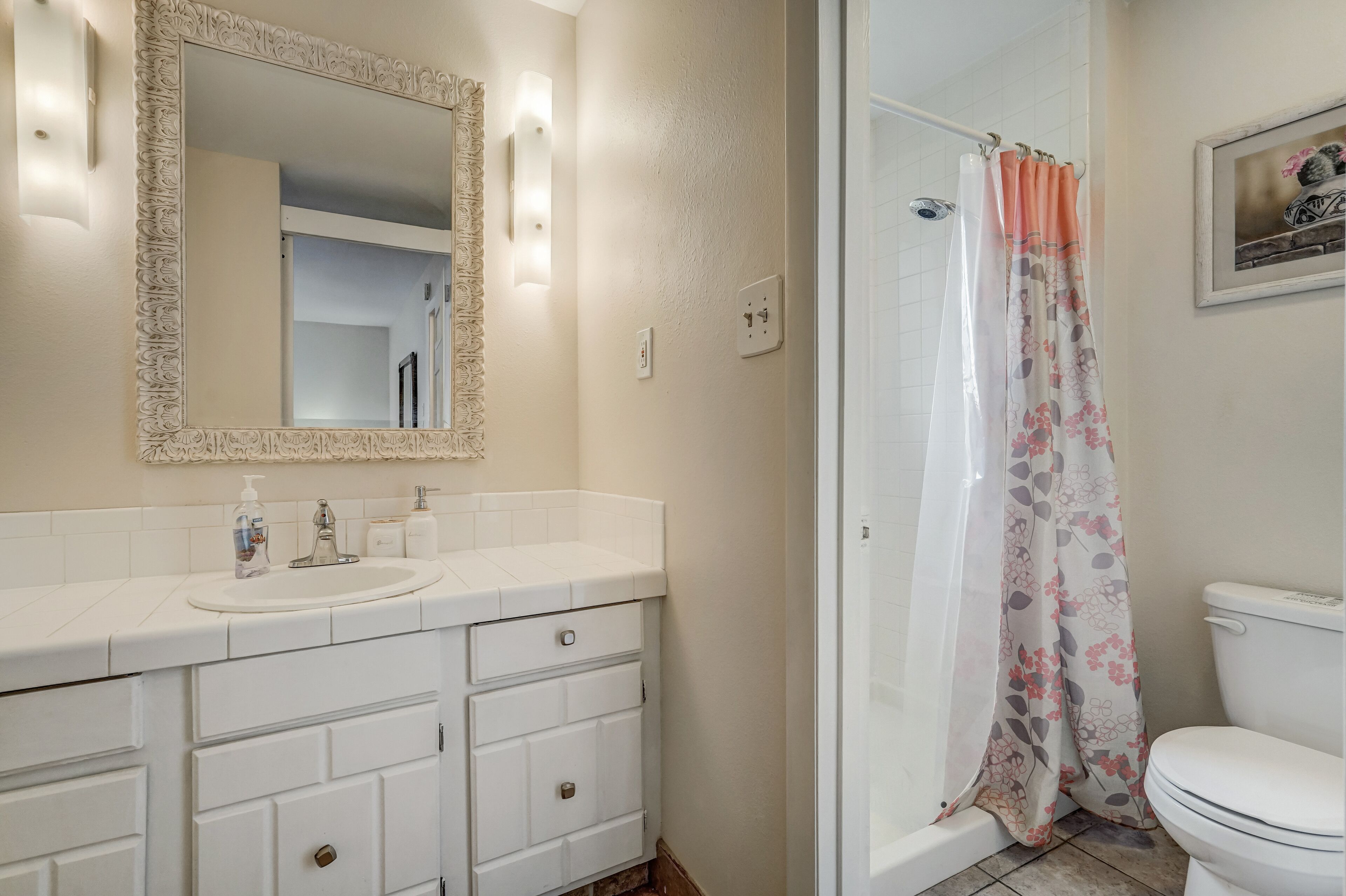Un baño con lavamanos, espejo y retrete blancos.