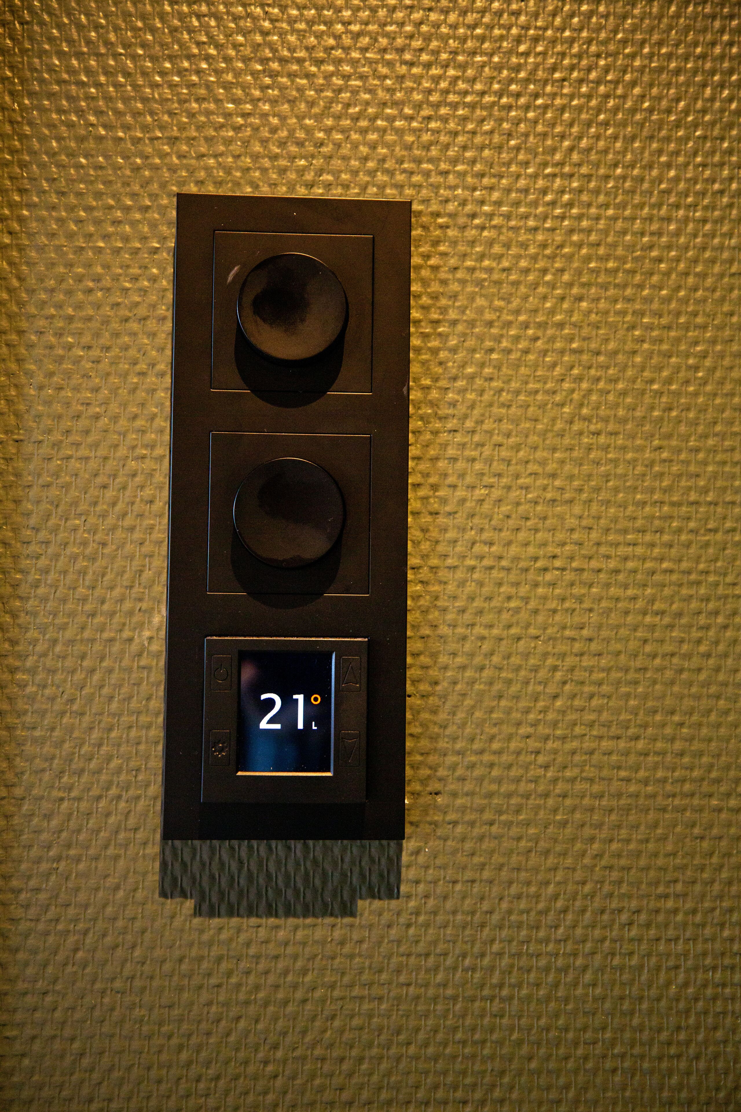A thermostat with a digital display showing 21 degrees.
