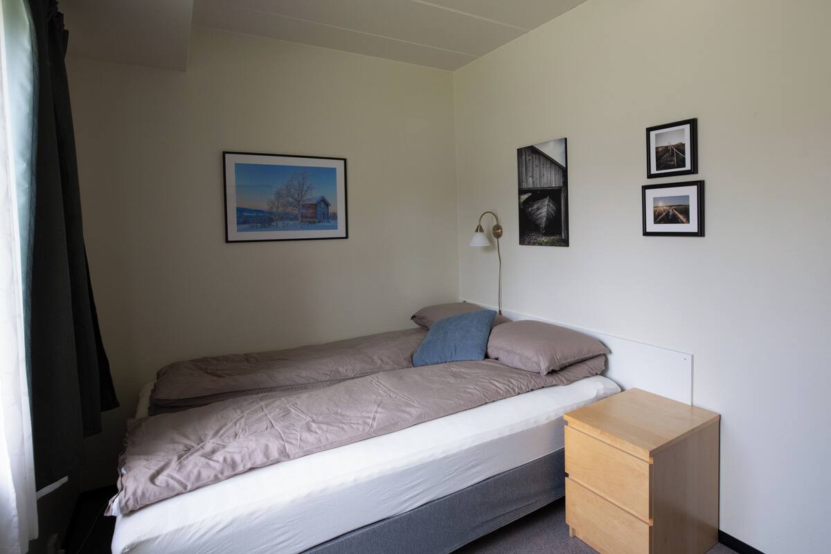 Ein Einzelbett mit Matratze, Kissen, einem Nachttisch und einer Wandlampe.