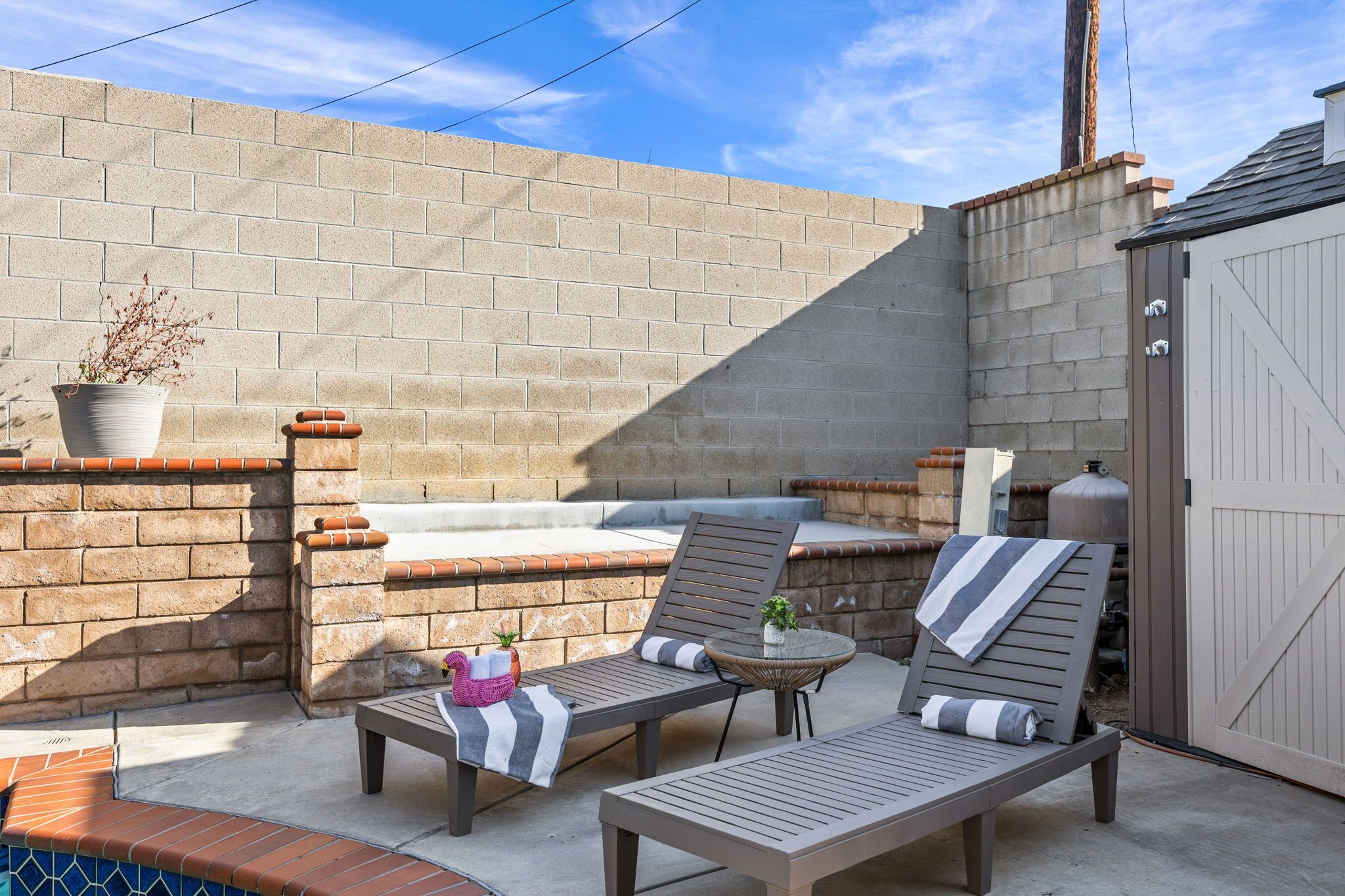 Un patio al aire libre con dos sillones, una mesita y una planta en maceta.
