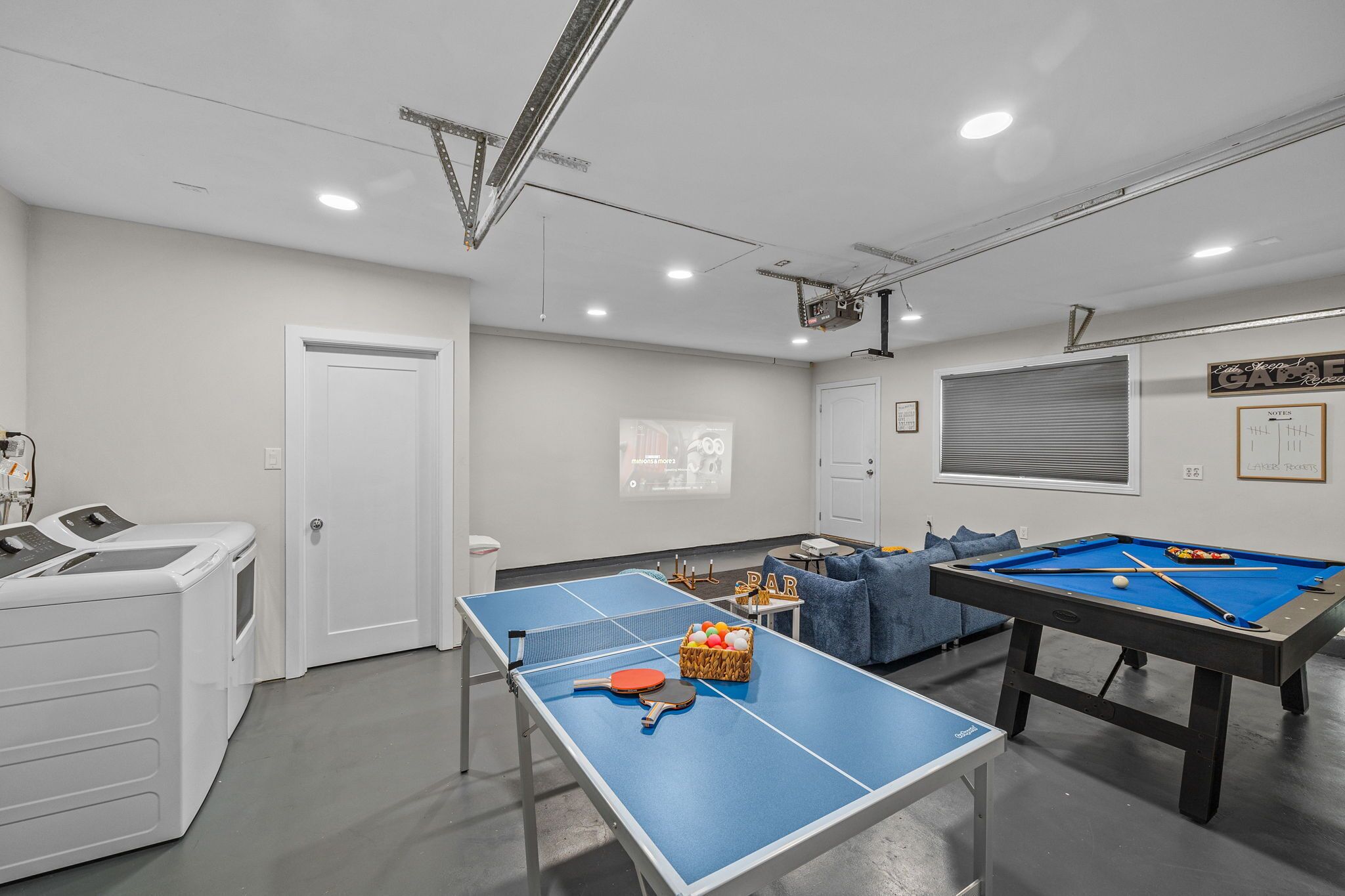 Quarto com mesa de pingue-pongue, mesa de bilhar e área de lavanderia.