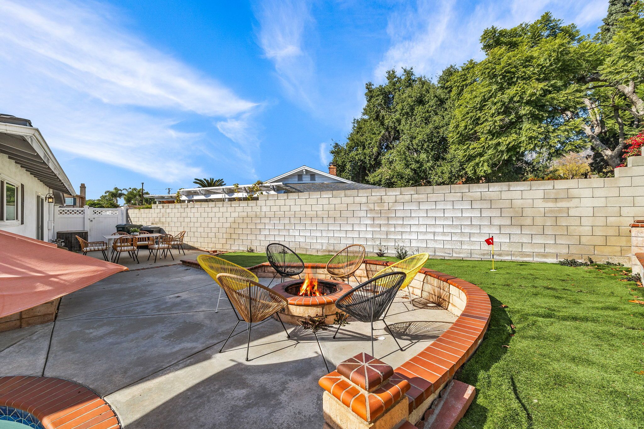 Un patio trasero con un hogar, mobiliario exterior y un muro de ladrillo.