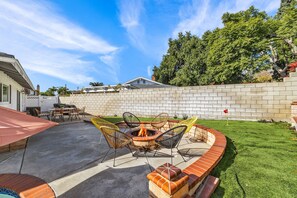 Un jardin avec un foyer, du mobilier d’extérieur et un mur en briques.